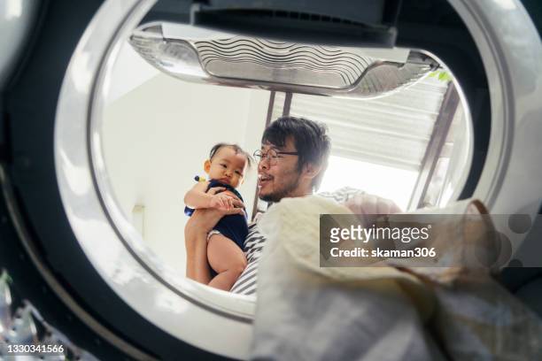 low angle view from inside washing machine asian single father embracing daughter feeling concern and boring about baby apron dirty and often to cleaning - laundry 個照片及圖片檔