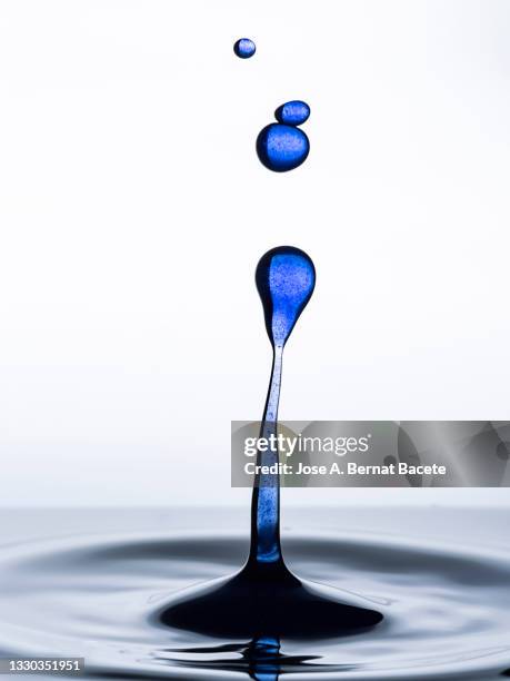 group of blue water droplets falling and splashing on a white background. - tropfen aufprall stock-fotos und bilder