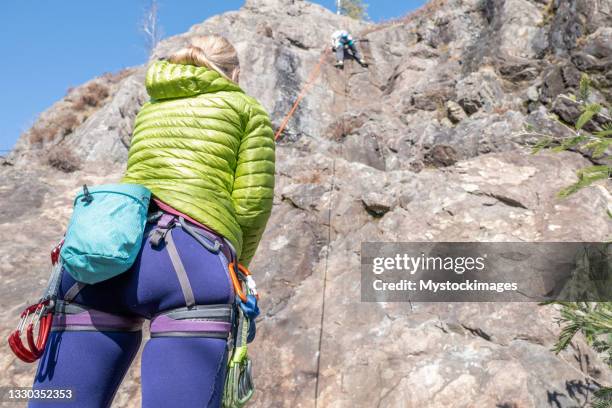 mountain climber belays teammate - zekeren stockfoto's en -beelden