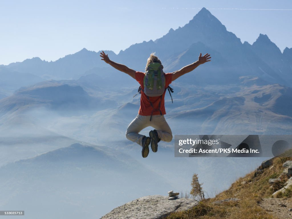 Hiker leaps into air above mtn path, clicks heels