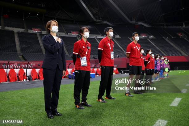 Asako Takakura, Head Coach of Team Japan wears a face mask during the national anthem with the backroom staff prior to the Women's First Round Group...