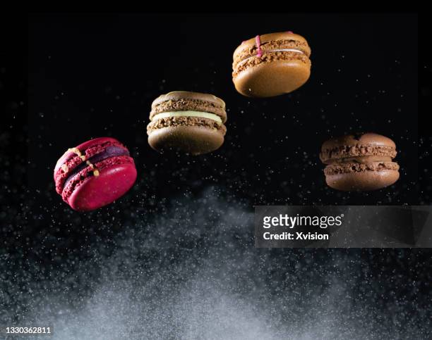 macarons dancing with black background in mid air captured with high speed sync."n - powdered sugar stock pictures, royalty-free photos & images