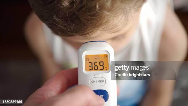 checking a boy's temperature - electronic-thermometers stock pictures, royalty-free photos & images
