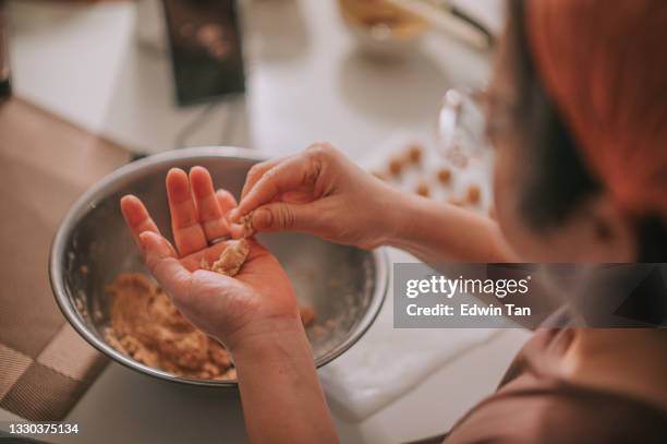 directly above top angle asian chinese mid adult woman hands press molding shape of peanut biscuit dough on palm of hand at home in the kitchen - gluten free bread stockfoto's en -beelden