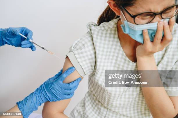 asian woman having trypanophobia (or needle phobia) while receiving vaccine injection. - sewing needle stock pictures, royalty-free photos & images