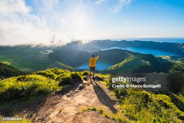 man on top of a mountain photographing volcanoes in sao miguel, azores - paysage voyage photos et images de collection