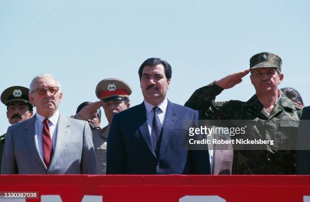 Flanked by unidentified Soviet officials, Afghan President Mohammad Najibullah attends the formal ceremony of the Soviet army withdrawal, Kabul,...