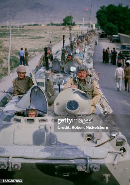 View of Soviet army soldiers as they ride on a line of armored vehicles during the Soviet troop withdrawal, Kabul, Afghanistan, April 30, 1988. They...