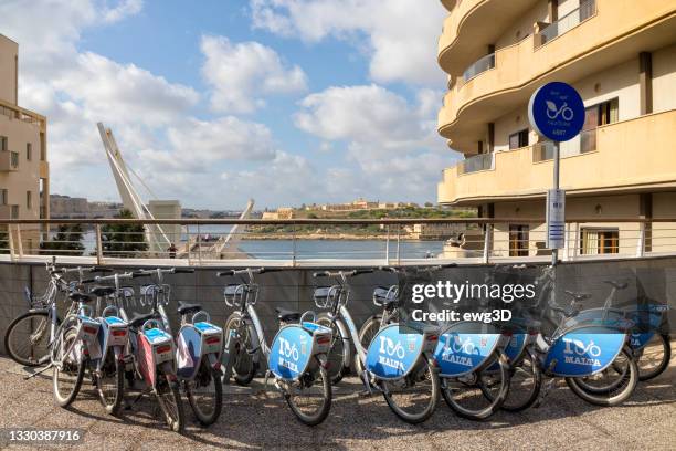 a row of city bikes for rent in malta - modern malta stock pictures, royalty-free photos & images