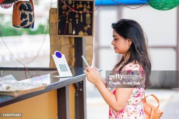 young female customer using digital payment method, scanning qr code with smartphone at a retail store to send money as payment using credit or debit card. - qr code stockfoto's en -beelden