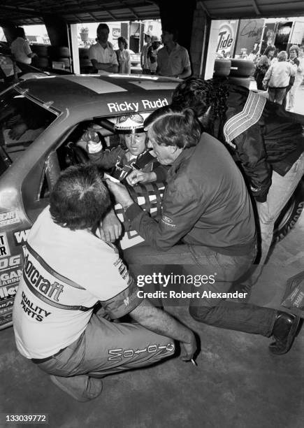 Driver Ricky Rudd sits in his race car as he talks with his car's owner, Bud Moore, in the Daytona International Speedway garage while crewmen make...