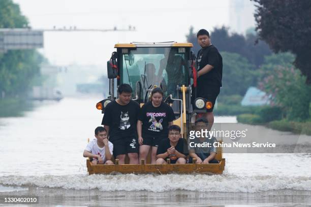 Rescuers use a front-end loader to evacuate local residents from a flood-hit area on July 24, 2021 in Xinxiang, Henan Province of China. Torrential...
