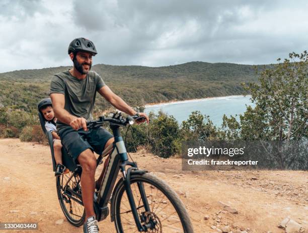 vater auf dem e-bike mit dem sohn - fahrradsattel stock-fotos und bilder