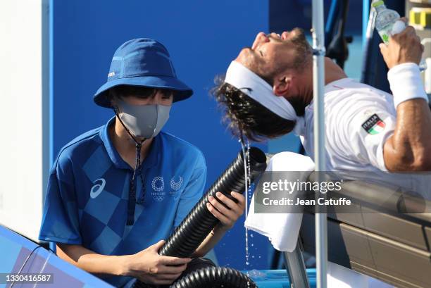 Fabio Fognini of Italy receives cool air from a machine held by a ball boy during day one of the Tokyo 2020 Olympic Games at Ariake Tennis Park on...