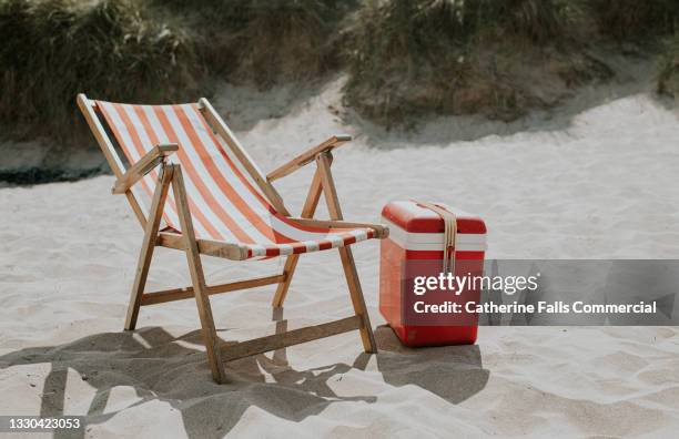 relaxing beach scene - a traditional deckchair and a matching retro cooler. - silla de playa fotografías e imágenes de stock