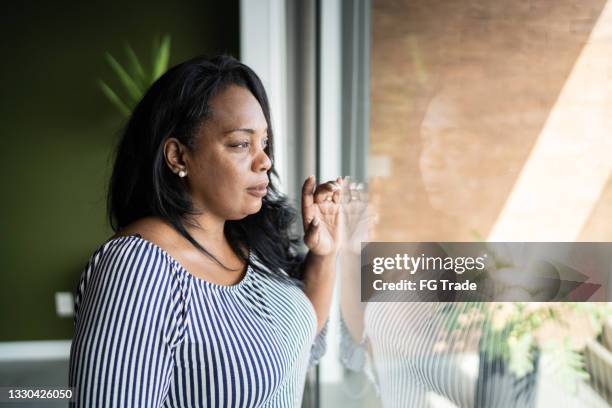 mature woman contemplating at home - black woman looking at view stock pictures, royalty-free photos & images