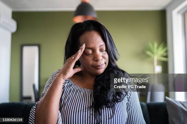 mature woman with headache at home - hoofdpijn vrouw stockfoto's en -beelden