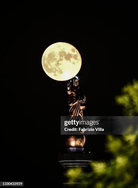 Full moon with the Madonnina of the Strait of Messina. Sicily on July 24, 2021 in Messina, Italy. The statue of “Madonna della Lettera” is erected at...