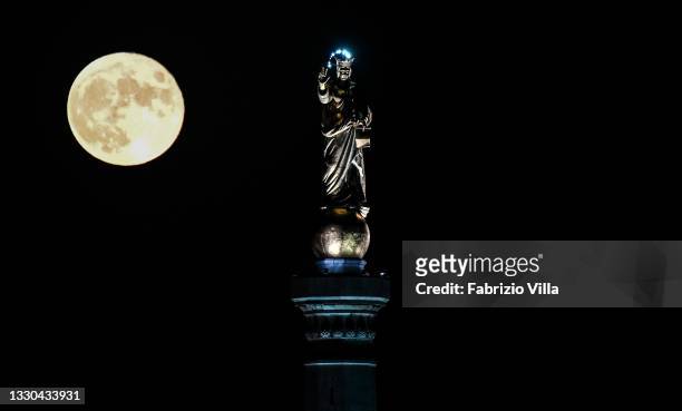 Full moon with the Madonnina of the Strait of Messina. Sicily on July 24, 2021 in Messina, Italy. The statue of “Madonna della Lettera” is erected at...