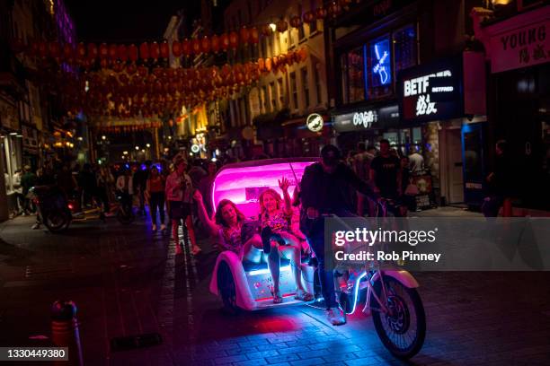 Group of women sing and dance in the back of an illuminated cycle rickshaw in Soho on July 25, 2021 in London, England. On Monday, July 19th the...