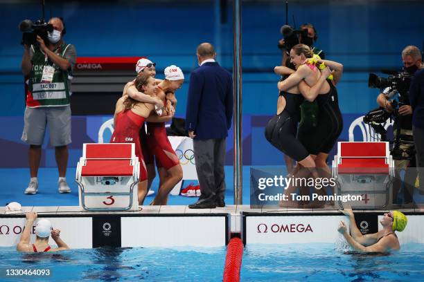 Members of Team Canada and Team Australia celebrate after competing in the Women's 4 x 100m Freestyle Relay Final on day two of the Tokyo 2020...