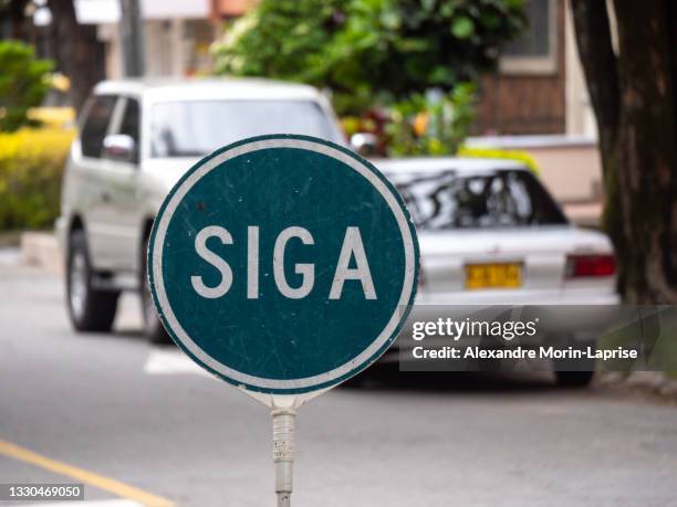 round blue road sign in the street that reads: "siga (continue)" - metro medellin stock pictures, royalty-free photos & images
