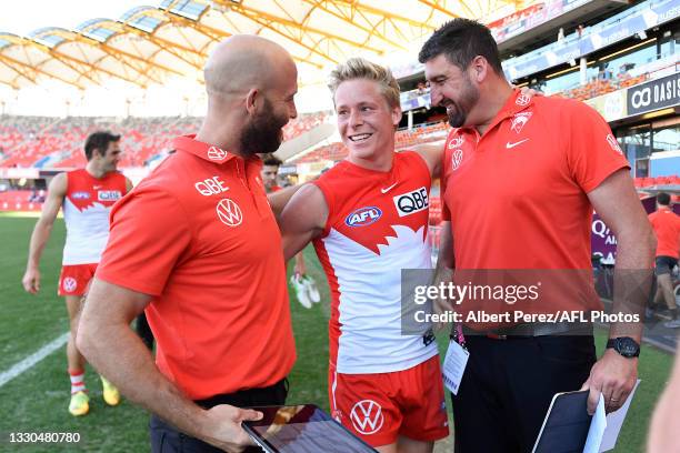 Isaac Heeney of the Swans is congratulated by assistant coaches Jarrad McVeigh and Dean Cox during the round 19 AFL match between Sydney Swans and...
