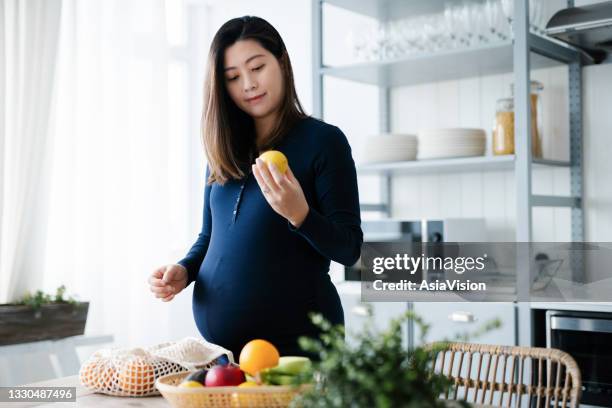 junge asiatische schwangere frau, die frisches und gesundes obst und gemüse einkauft und in einer gesunden und ausgewogenen ernährung lebt. gut essen. wohlsein. gesunder schwangerschaftslebensstil - sustainable living stock-fotos und bilder