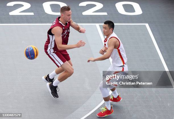 Shiyan Gao of Team China passes under pressure from Karlis Lasmanis of Team Latvia during the Men's Pool Round match between China and Latvia on day...