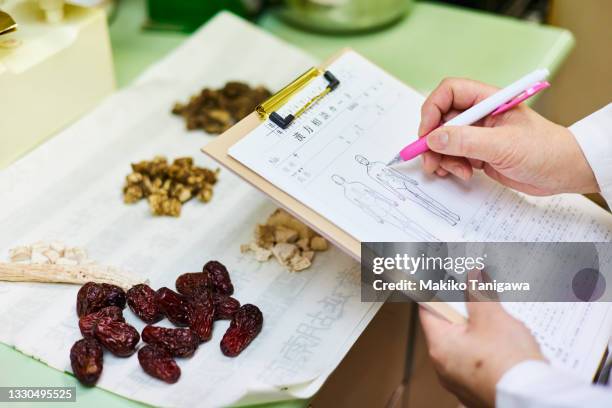 chinese medicine doctor writing in medical records - japanese ethnicity the human body stock pictures, royalty-free photos & images