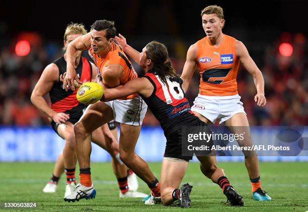 Isaac Cumming of the Giants is tackled during the round 19 AFL match between Essendon Bombers and Greater Western Sydney Giants at Metricon Stadium...