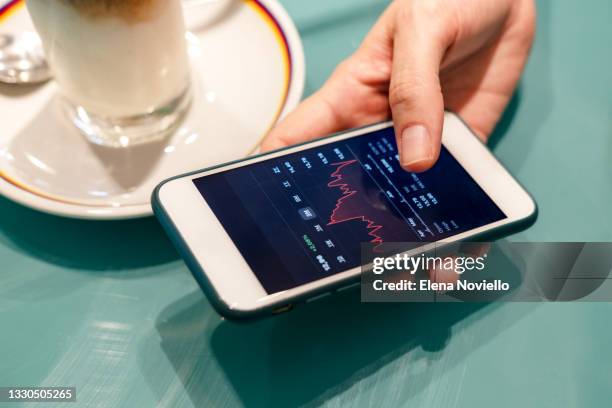 stock market investor woman hands holding a phone investment app index growth chart - financial technology stock-fotos und bilder