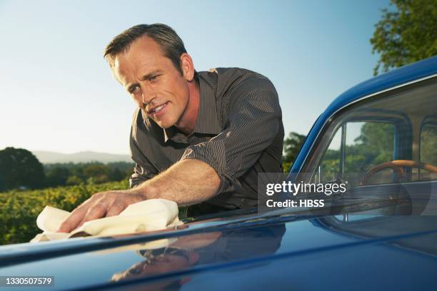 mature man polishing vintage car - símbolo de status imagens e fotografias de stock