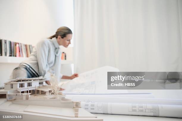 female architect sitting on the floor examining construction plan - architekt modell stock-fotos und bilder