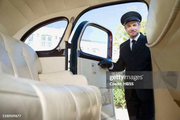 chauffeur opening door of a vintage car - chauffeur 個照片及圖片檔