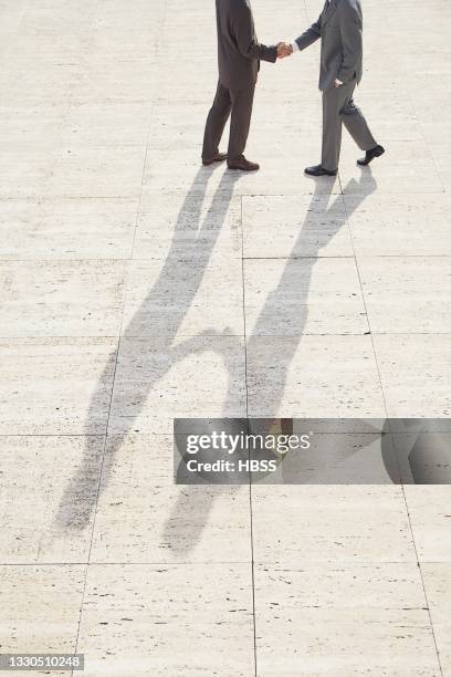 two businessmen shaking hands on a square - shaking leg stock pictures, royalty-free photos & images