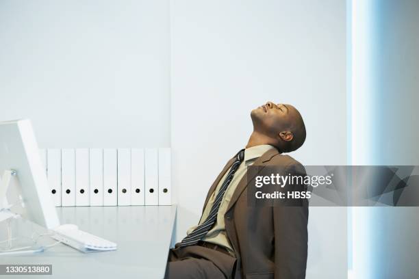 tired young businessman napping at desk in office - head back stock pictures, royalty-free photos & images