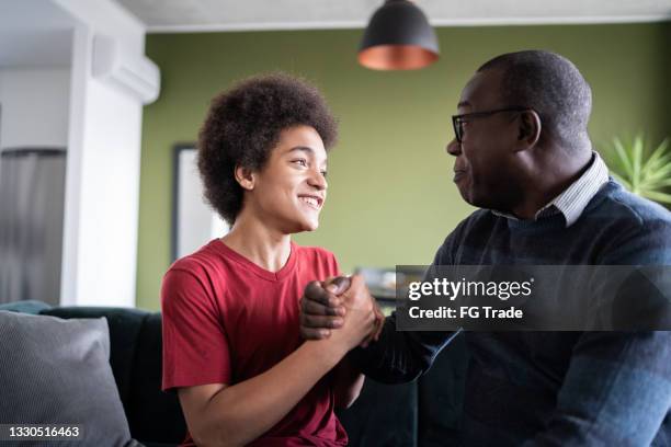 father and son together holding hands sitting on the couch at home - stay at home saying 個照片及圖片檔