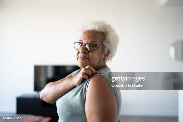 retrato de uma idosa mostrando braço para tomar vacina - 65 69 anos - fotografias e filmes do acervo