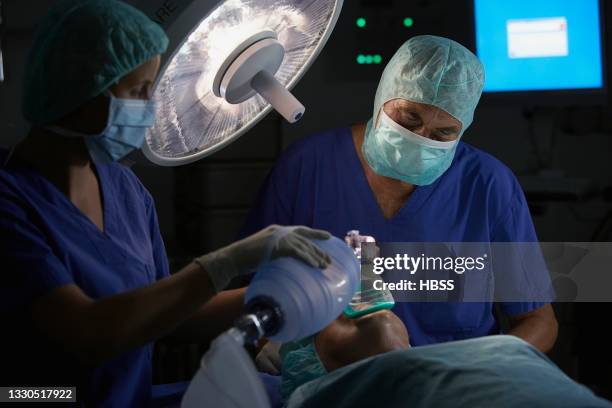 two doctors anaesthetizing patient in operation room - anesthesia mask foto e immagini stock
