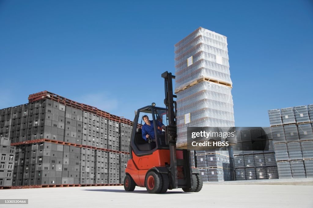 Worker driving forklift on factory yard