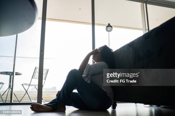 depressed mature woman sitting on the ground at home - anxiety disorder stock pictures, royalty-free photos & images
