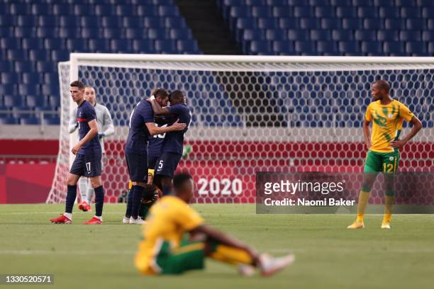 Andre-Pierre Gignac and Niels Nkounkou of Team France celebrate their side's victory as Eboue Kouassi of Team South Africa looks dejected after the...