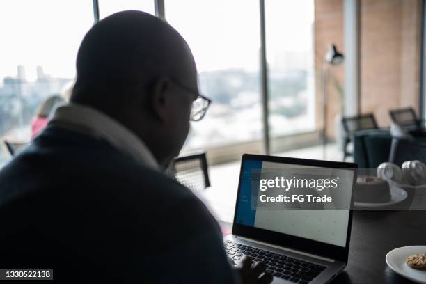 mature man using laptop working at home - online calendar stock pictures, royalty-free photos & images