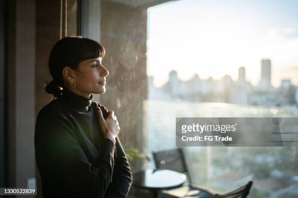 mujer joven contemplando en casa - tranquilidad fotografías e imágenes de stock