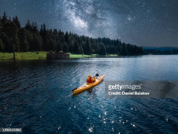 woman kayaking in mountain lake under milky way. aerial view with starry sky. paddling and ecotourism. - kayaking stock pictures, royalty-free photos & images