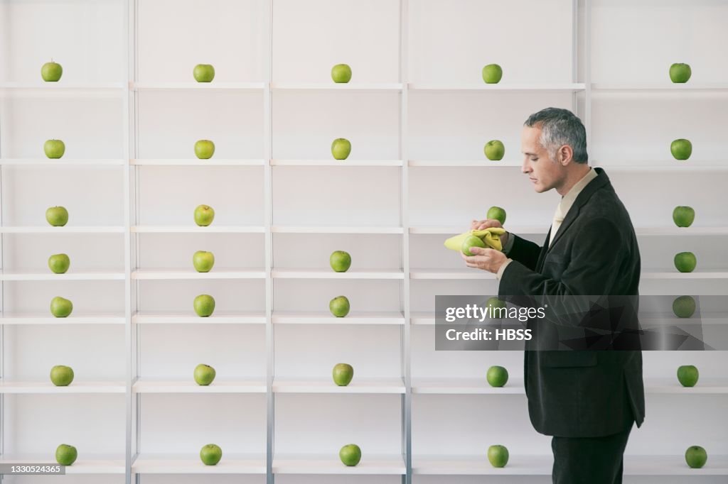 Mature businessman cleaning green apple at a shelf