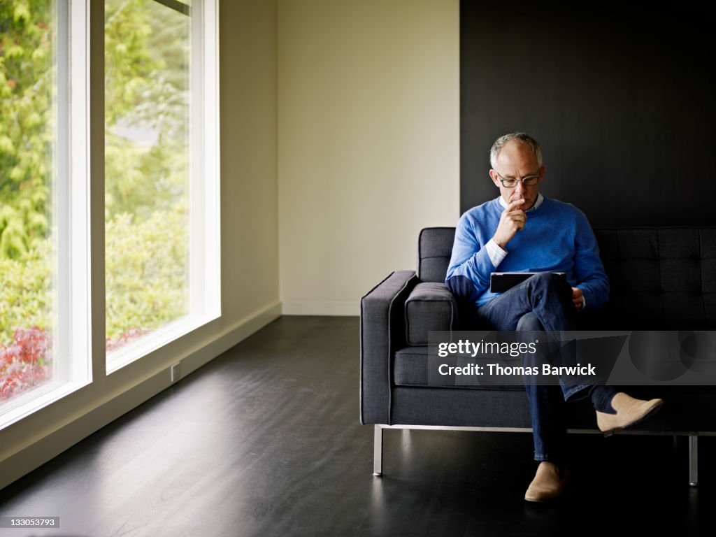 Mature man sitting looking at digital tablet