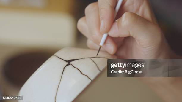 woman repairing broken pottery. kintsugi. - handmade stockfoto's en -beelden