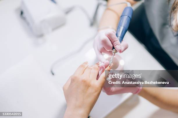 the specialist processes nails with manicure machine - milling cutter stock pictures, royalty-free photos & images